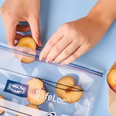 Hände legen Pflaumenhälften in einen Toppits SafeLoc Beutel zum Einfrieren. So bleiben die Früchte lange frisch.