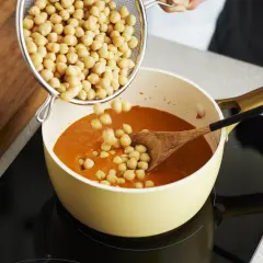 Kichererbsen werden in einen Topf mit Curry gegeben. Perfekt für die Zubereitung von Kichererbsen-Curry zum Einfrieren.