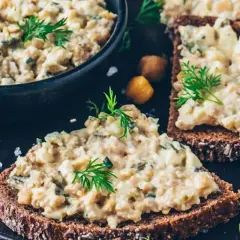 Herzhaft belegtes Brot mit cremigem veganem Thunfisch-Salat, garniert mit Dill und Kichererbsen.