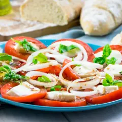 Tomaten-Mozzarella-Salat mit Zwiebelringen und Basilikum, beträufelt mit einem leckeren Dressing. Dazu frisches Brot.