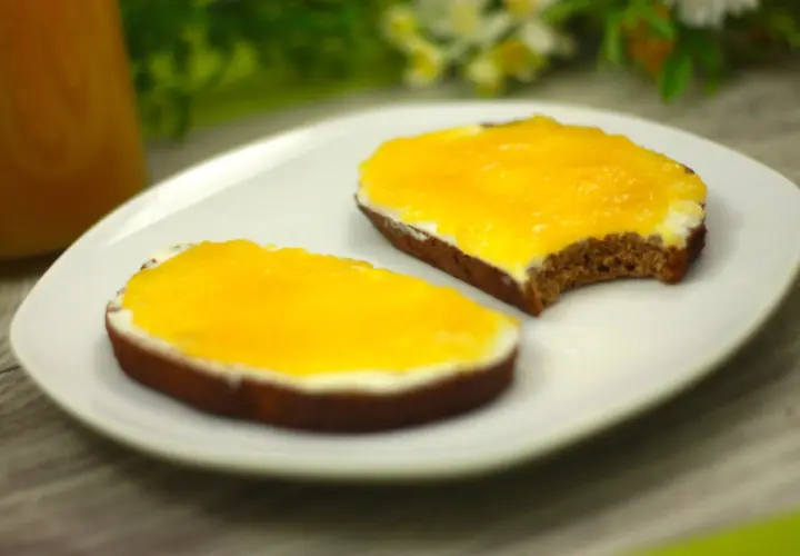 Zwei Scheiben Brot mit Frischkäse und leuchtend gelber, selbstgemachter low carb Marmelade.