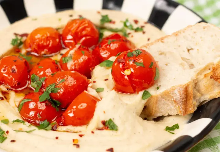 Cremiger veganer Tomatenaufstrich mit gerösteten Kirschtomaten, Kräutern und Brot.