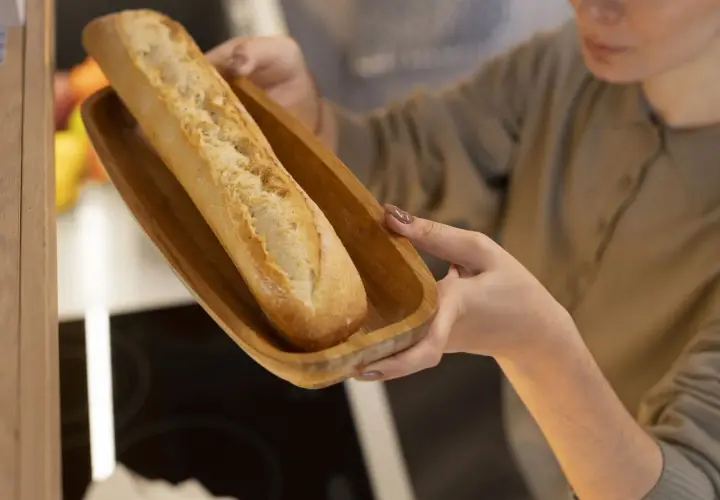 Frau hält Holzschale mit Baguette zum Auftauen.