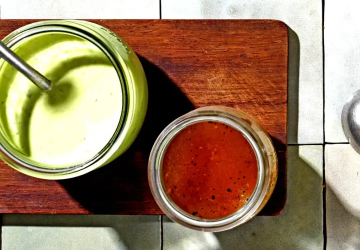Zwei Gläser mit Saucen: ein cremiges Avocado Dressing für Salat und eine rote Vinaigrette.