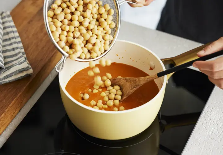 Kichererbsen werden in einen Topf mit Curry gegeben. Perfekt für die Zubereitung von Kichererbsen-Curry zum Einfrieren.