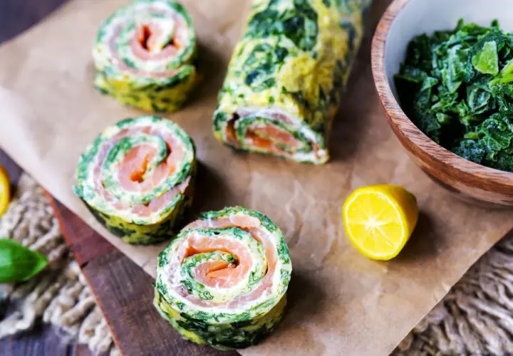 Spinat-Lachs-Röllchen, eine köstliche low carb Mahlzeit. Serviert mit frischem Spinat und Zitrone.