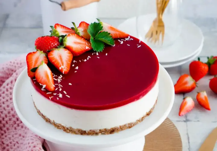 Ein köstlicher veganer Cheesecake ohne Backen, dekoriert mit frischen Erdbeeren und einem glänzenden Fruchtspiegel.