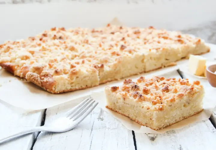 Ein Stück saftiger low carb streusel Kuchen mit Butter und einer Gabel auf einem Holztisch.