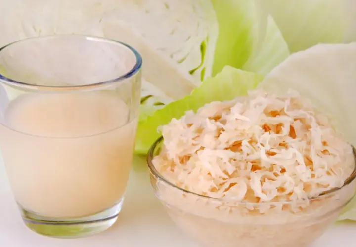 Glas mit Sauerkrautsaft, Schüssel mit Sauerkraut und Weißkohl. Ideal für eine Sauerkrautsaft Kur. Anleitung hier.