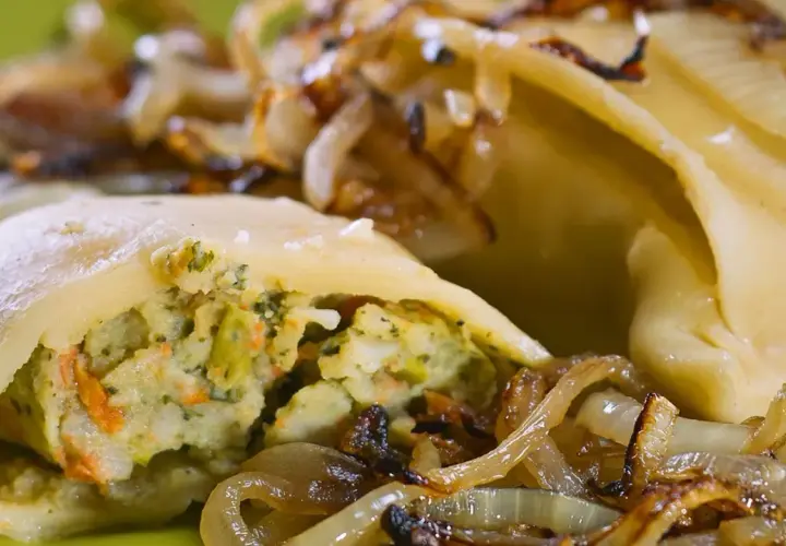 Maultaschen low carb gefüllt mit Gemüse, serviert mit karamellisierten Zwiebeln auf einem grünen Teller.