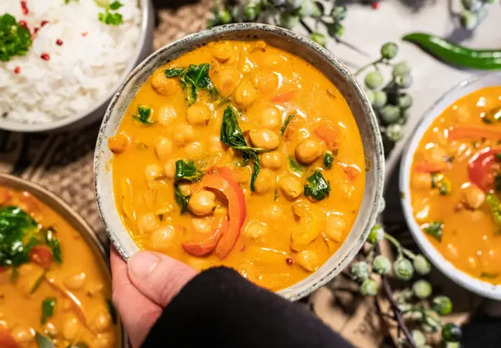 Ein köstliches veganes Curry mit Kichererbsen, Paprika und Spinat in cremiger Sauce, serviert mit Reis.