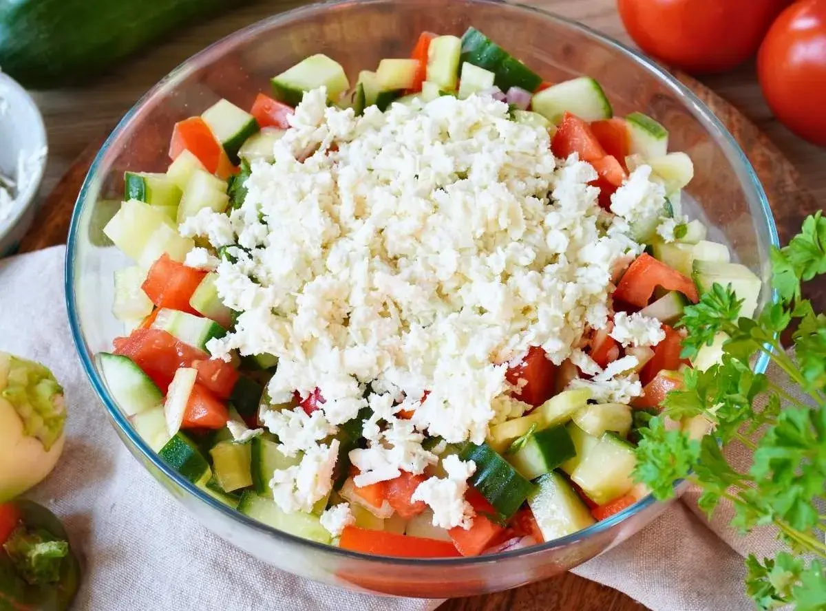 Frischer Schopska Salat mit viel Feta-Käse, Tomaten und Gurken in einer Glasschüssel.