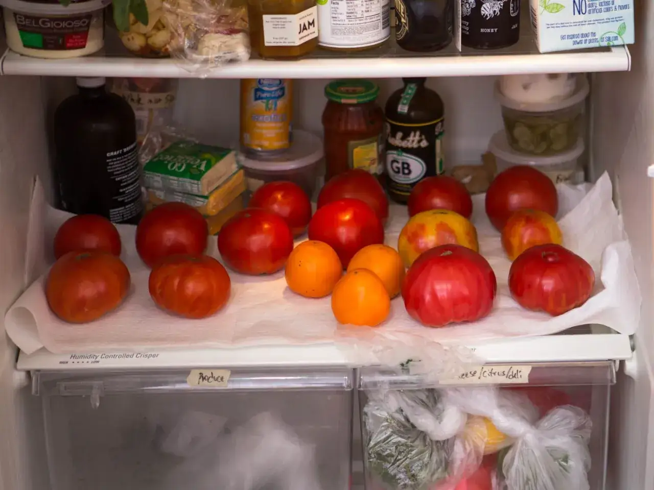 Frische Tomaten lagern auf Küchenpapier im Kühlschrank. Verschiedene Sorten und Größen, von leuchtend rot bis orange.