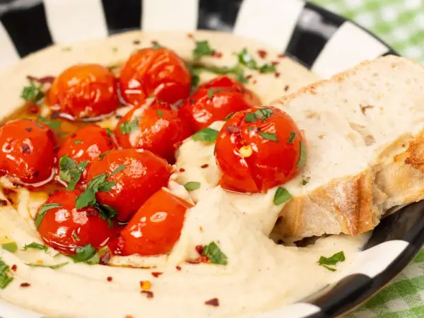 Cremiger veganer Tomatenaufstrich mit gerösteten Kirschtomaten, Kräutern und Brot.